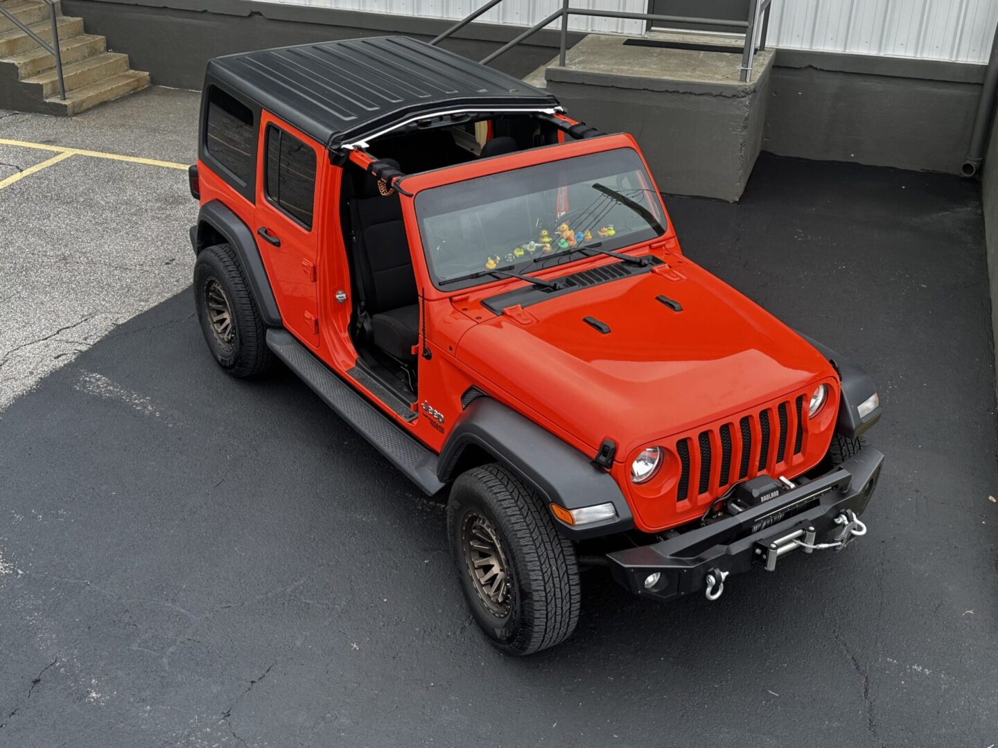 A red jeep parked in the driveway of a house.